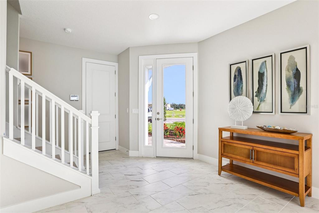 A bright entryway features white tile floors, a wooden console table, and a white staircase — 31515 SPANISH MISSION ROAD, SAN ANTONIO, FL