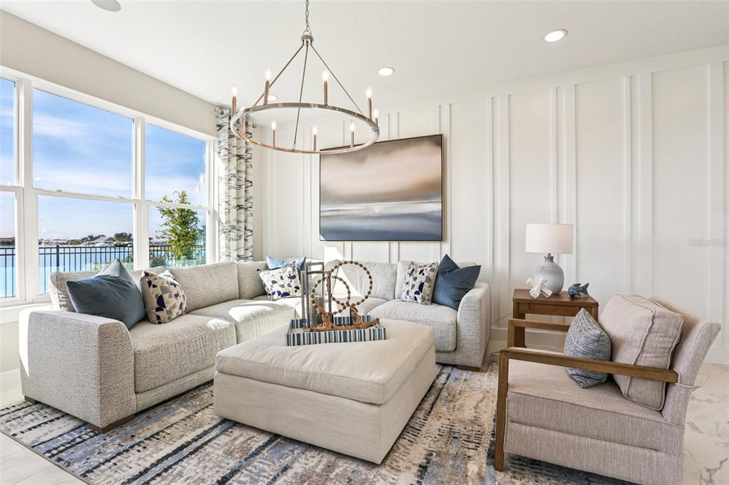 A living room features a sectional sofa, ottoman, and large window overlooking a lake — 31515 SPANISH MISSION ROAD, SAN ANTONIO, FL