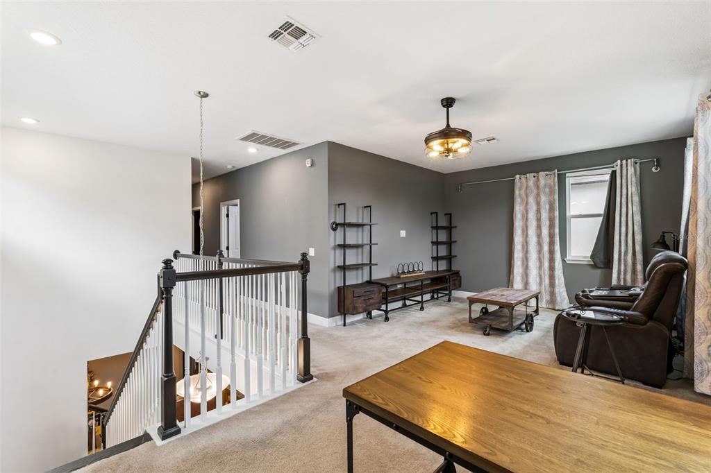 A loft area features gray walls, carpeted flooring, a ceiling fan, and a wooden desk — 9354 MEADOW HUNT WAY, WINTER GARDEN, FL