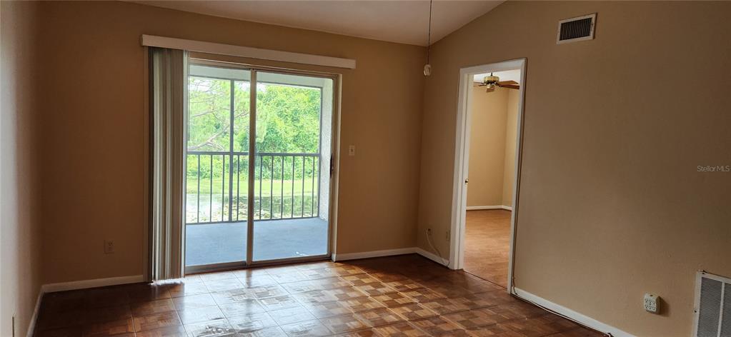 A room with tiled floors, a sliding glass door to a balcony, and an interior doorway — 11201 122ND AVENUE UNIT L-232, LARGO, FL