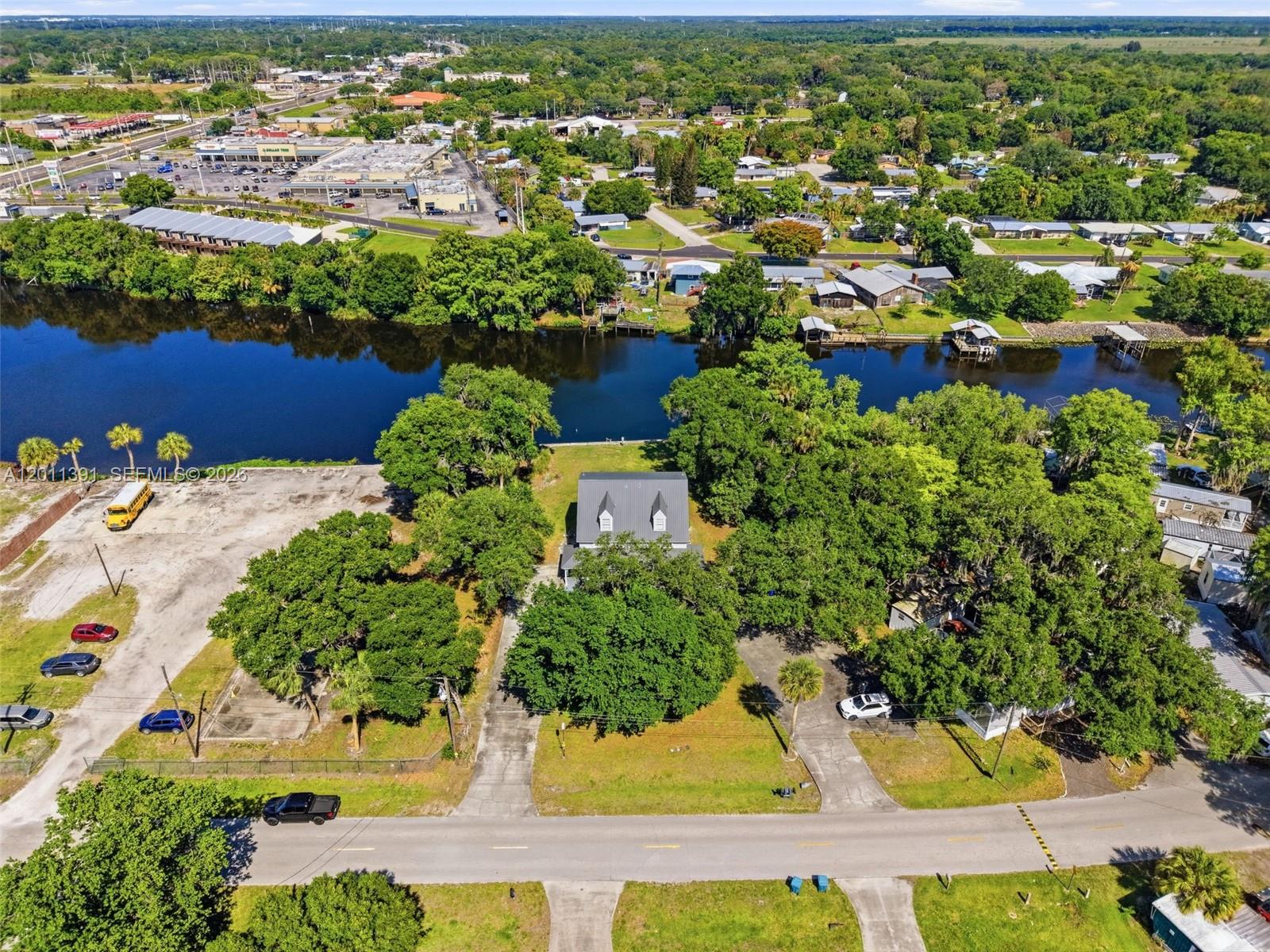An aerial view shows a house with a gray roof situated on a waterfront lot — 207 SE 6TH Avenue, Okeechobee FL 34974, OKEECHOBEE, FL