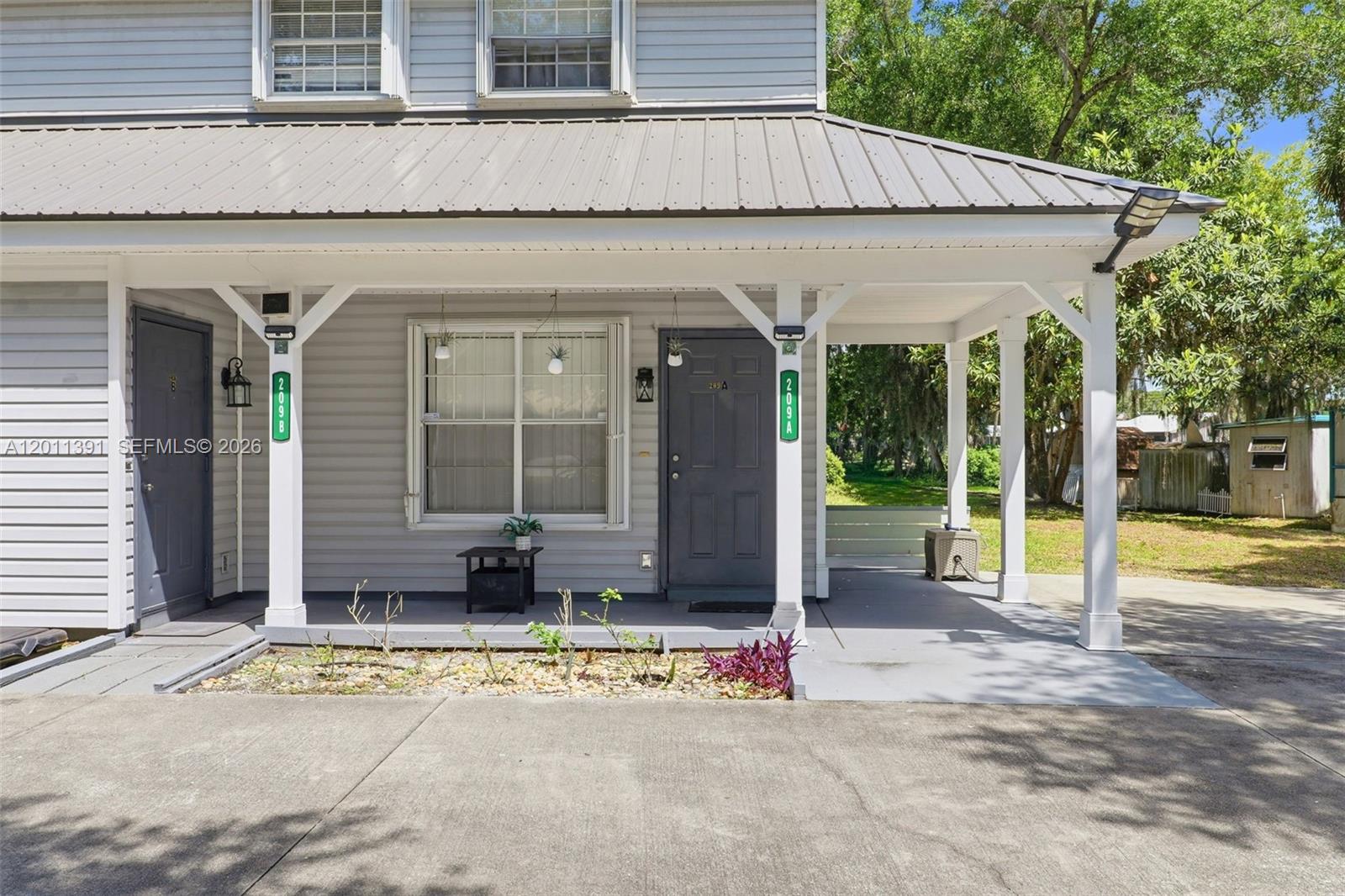 The exterior of a two-story house features a covered front porch with two entry doors — 207 SE 6TH Avenue, Okeechobee FL 34974, OKEECHOBEE, FL