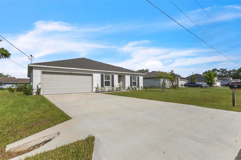 A single-story house with a white exterior, a two-car garage, and a concrete driveway — 22 ROUND TREE DRIVE, PALM COAST, FL