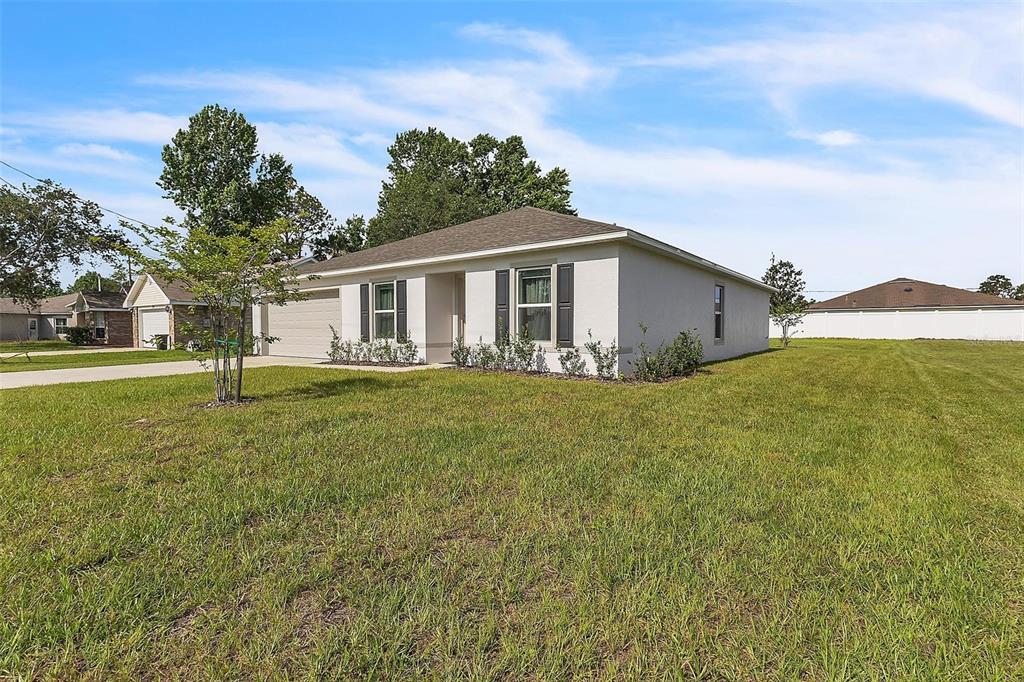 A single-story house with a beige exterior, a two-car garage, and a large grassy yard — 22 ROUND TREE DRIVE, PALM COAST, FL
