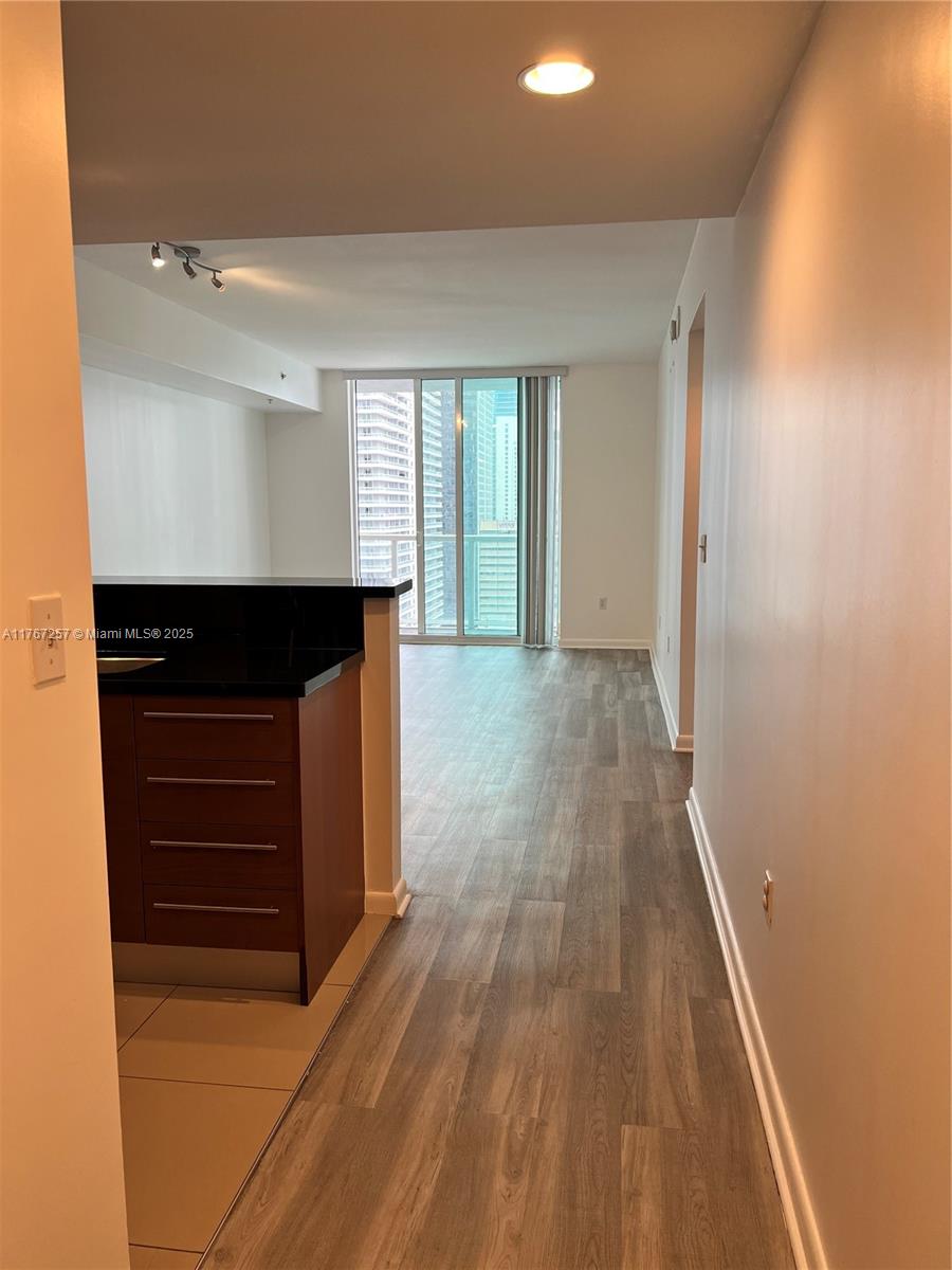 An interior view shows a kitchen with dark cabinets and a living area with balcony access — 244 Biscayne Blvd # 2609, Miami FL 33132, MIAMI, FL