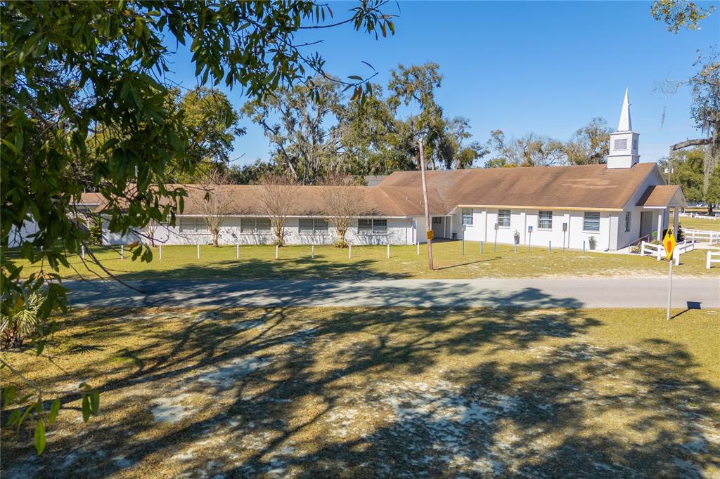A low-slung white church building with a steeple sits behind a grassy lawn — 6104 POLK AVENUE NW, LAKELAND, FL