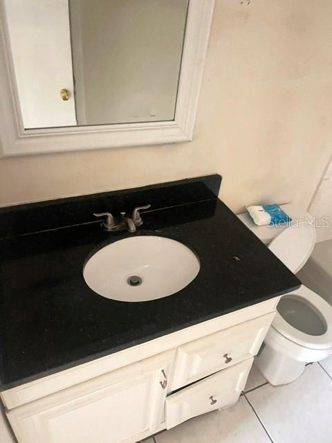 A bathroom features a white vanity with a black countertop, a sink, and a toilet — 5206 CURRY FORD ROAD UNIT 113, ORLANDO, FL