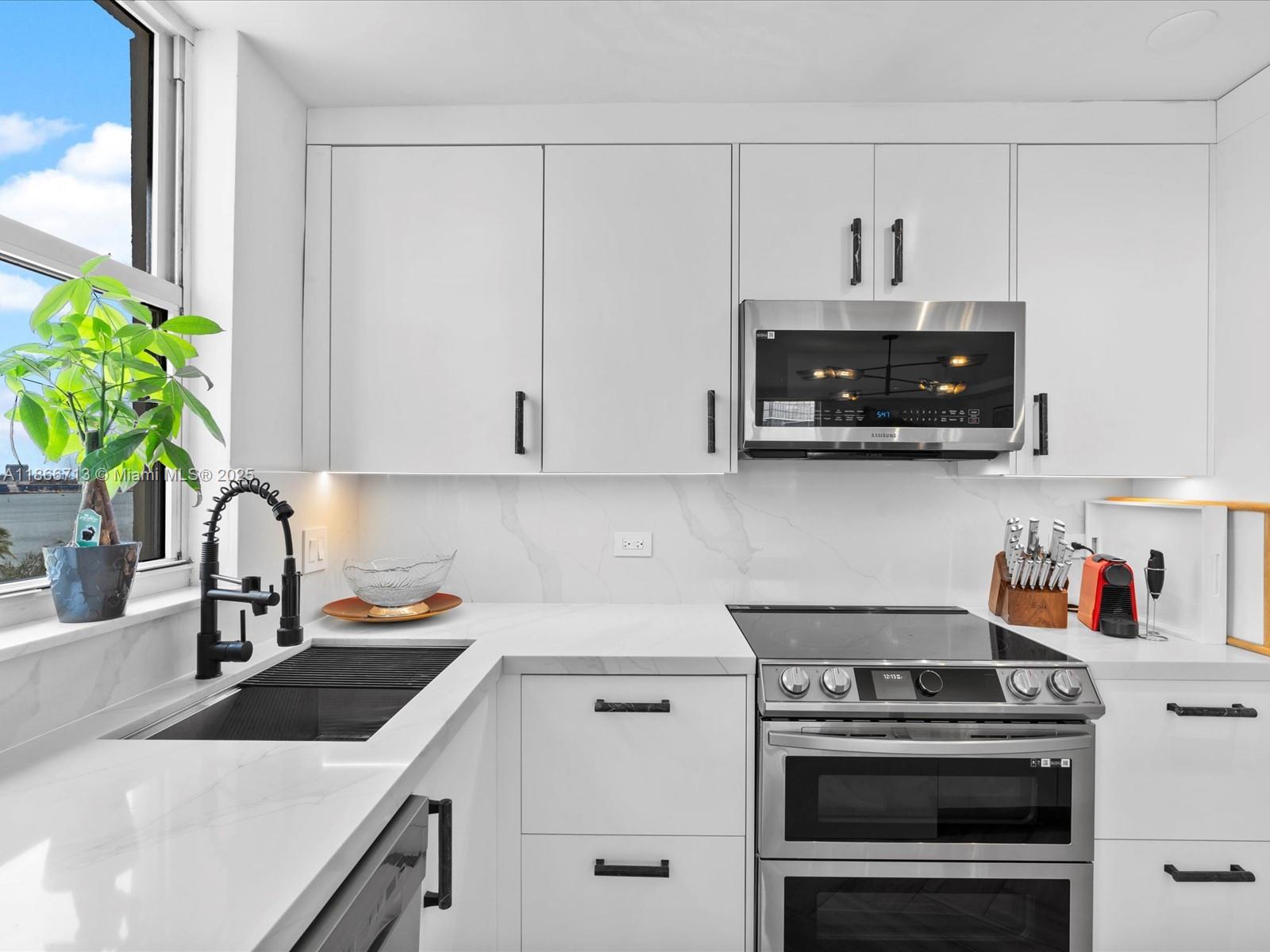 A modern kitchen features white cabinets, stainless steel appliances, and a marble-patterned countertop — 770 Claughton Island Dr # 701, Miami FL 33131, MIAMI, FL