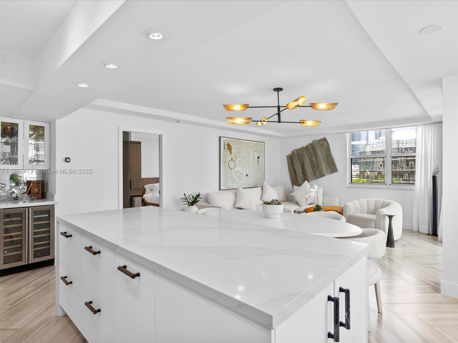 A white kitchen island with marble countertops sits in a modern open-concept living area — 770 Claughton Island Dr # 701, Miami FL 33131, MIAMI, FL