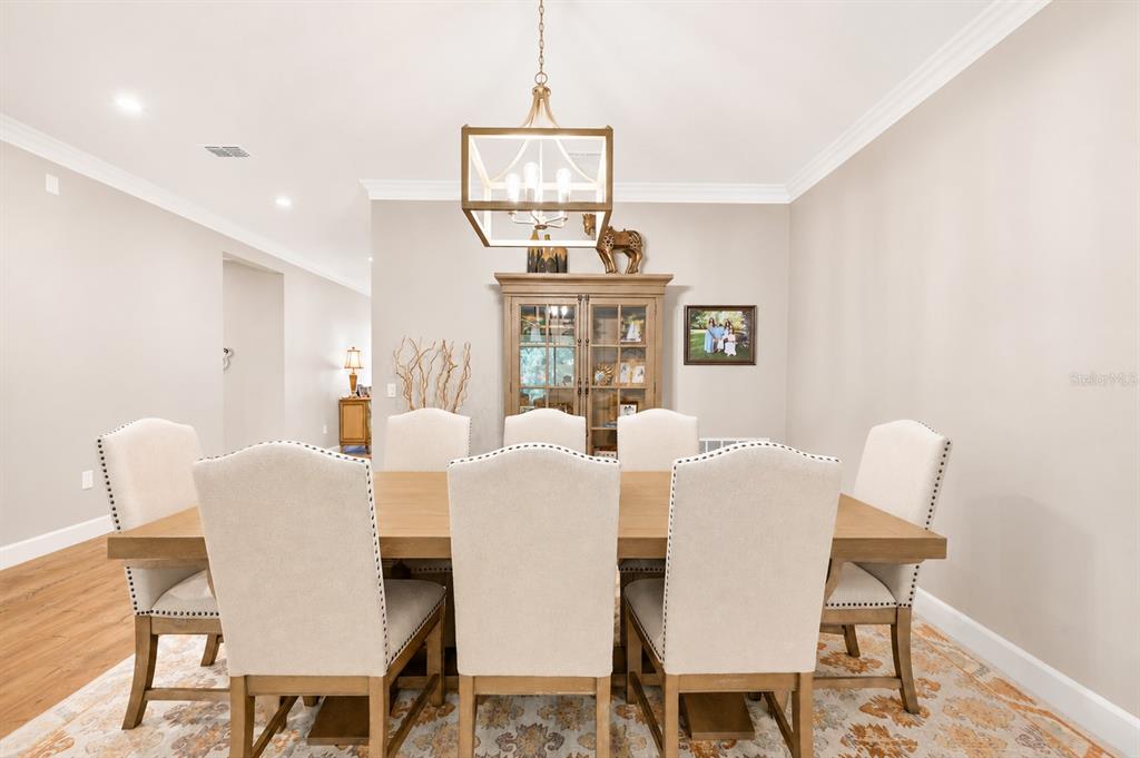 A dining room features a wooden table with six upholstered chairs under a rectangular chandelier — 3870 BOWFIN TRAIL, KISSIMMEE, FL