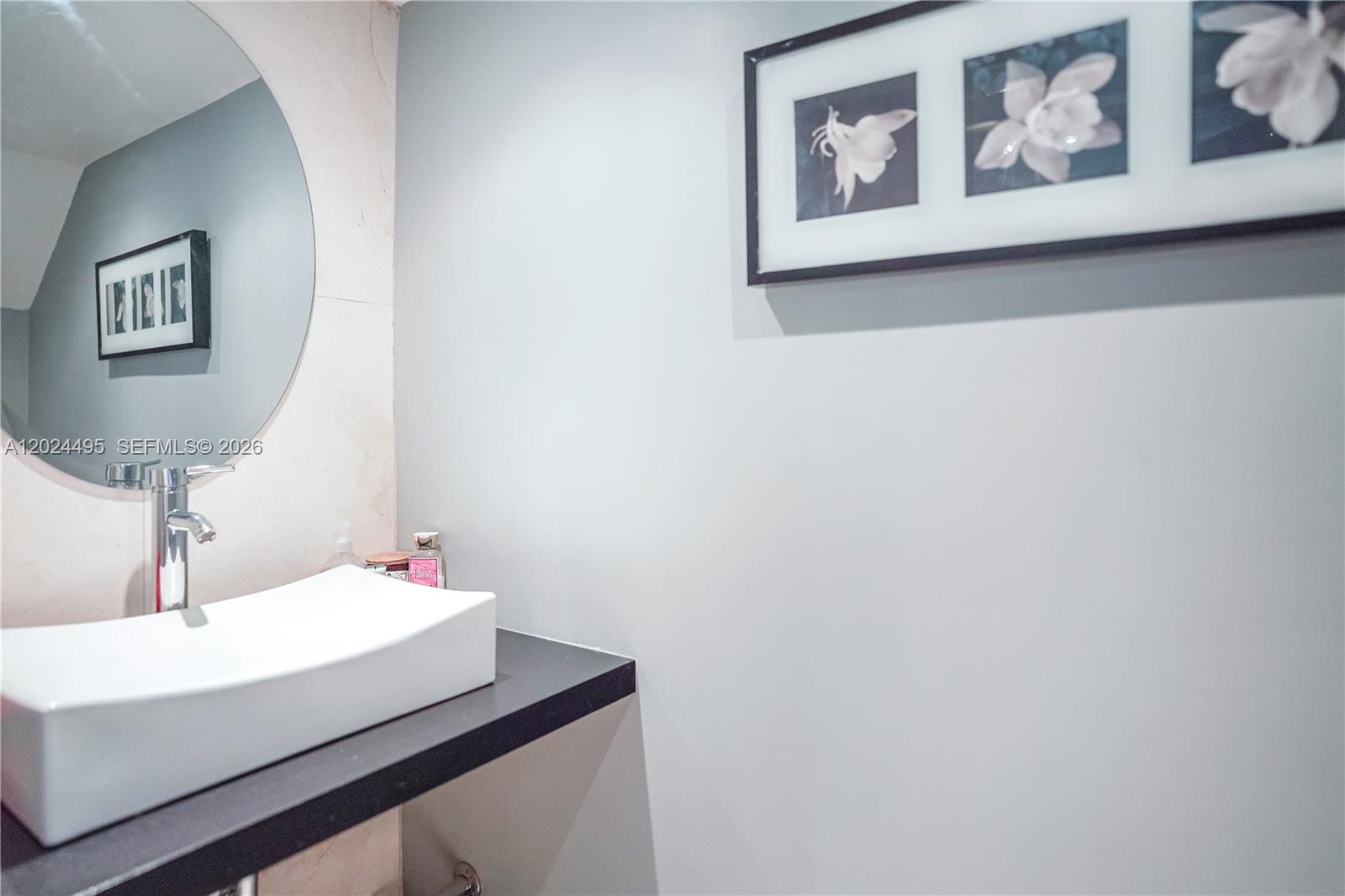 A modern bathroom features a white vessel sink on a black counter and wall art — 18101 NW 68th Ave # C204, Hialeah FL 33015, HIALEAH, FL