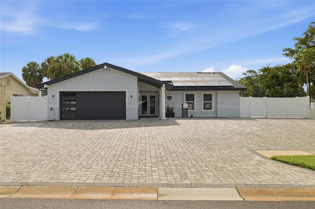 A single-story house with a large paver driveway, dark garage door, and solar panels — 7101 SHENANDOAH COURT, TAMPA, FL