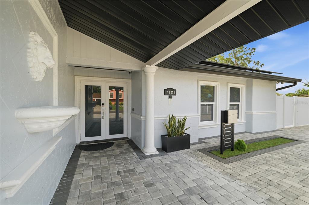 The exterior entrance features a paved walkway, a white column, and a lion head fountain — 7101 SHENANDOAH COURT, TAMPA, FL