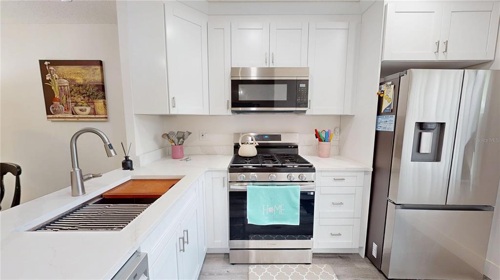 A kitchen features white cabinets, stainless steel appliances, and a light-colored countertop — 1418 ARROWHEAD CIRCLE W UNIT 20D, CLEARWATER, FL