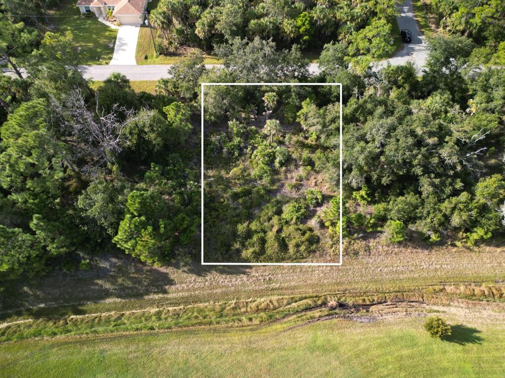 An aerial view shows a rectangular, wooded vacant lot outlined in white near a road — 0 CELEST STREET, NORTH PORT, FL