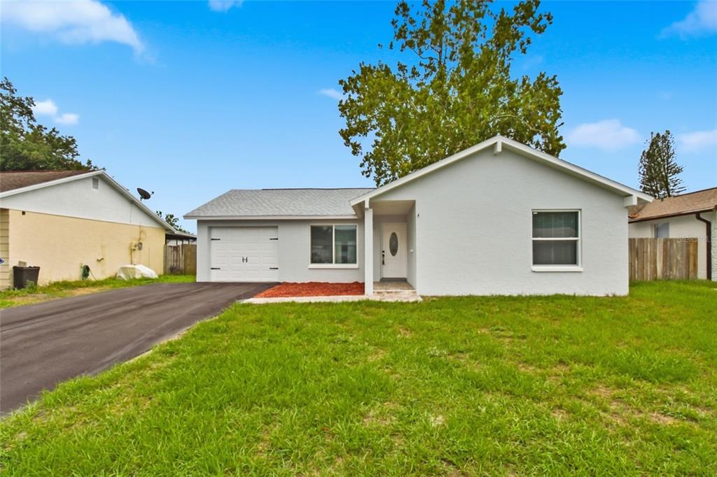 A single-story house with a light gray exterior, a front-facing garage, and a paved driveway — 7342 IVORY TERRACE, NEW PORT RICHEY, FL