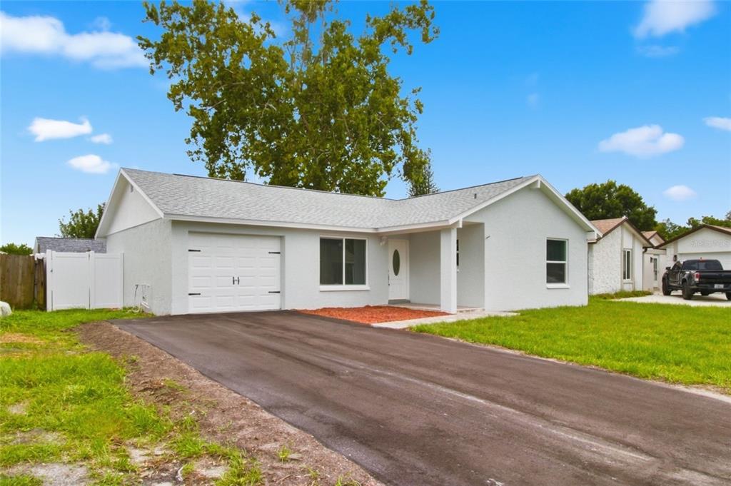 A single-story house with a white exterior, a one-car garage, and a paved driveway — 7342 IVORY TERRACE, NEW PORT RICHEY, FL