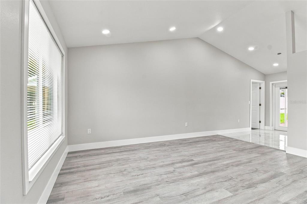 A bright room with light gray walls, wood-look flooring, recessed lighting, and a large window — 7342 IVORY TERRACE, NEW PORT RICHEY, FL