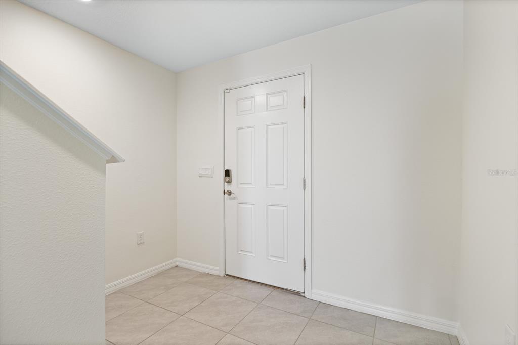 A white door with a smart lock opens into a small entryway with tiled flooring — 16555 MOSAIC OAR DRIVE, WIMAUMA, FL