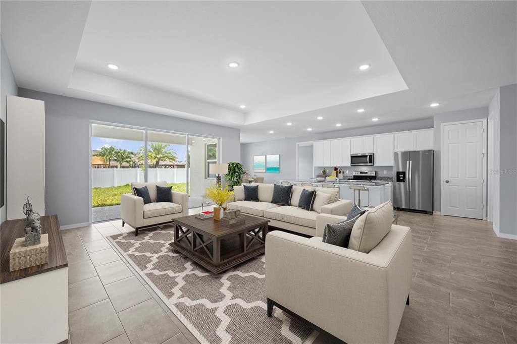A bright open-concept living room features a tray ceiling, tile flooring, and a modern kitchen — 271 MUNOZ STREET, PORT CHARLOTTE, FL