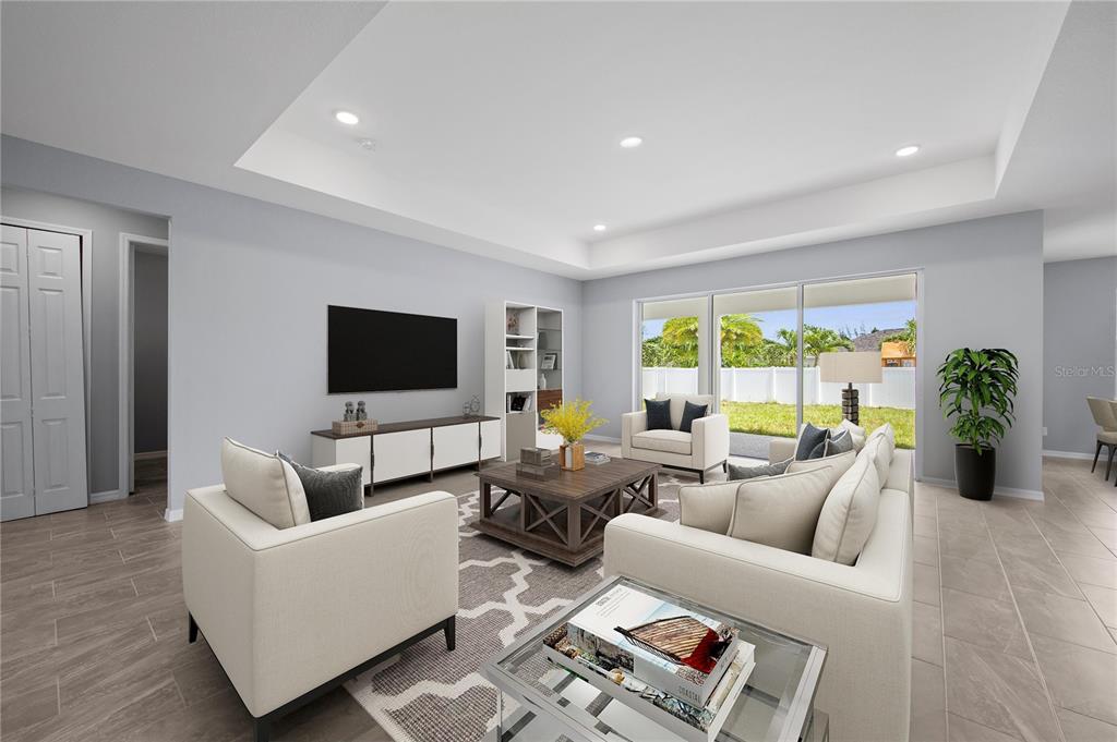 A living room with a tray ceiling, tile floors, neutral furniture, and sliding glass doors — 271 MUNOZ STREET, PORT CHARLOTTE, FL