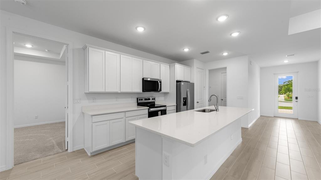 A modern kitchen features white cabinets, a large island with a sink, and light tile flooring — 271 MUNOZ STREET, PORT CHARLOTTE, FL