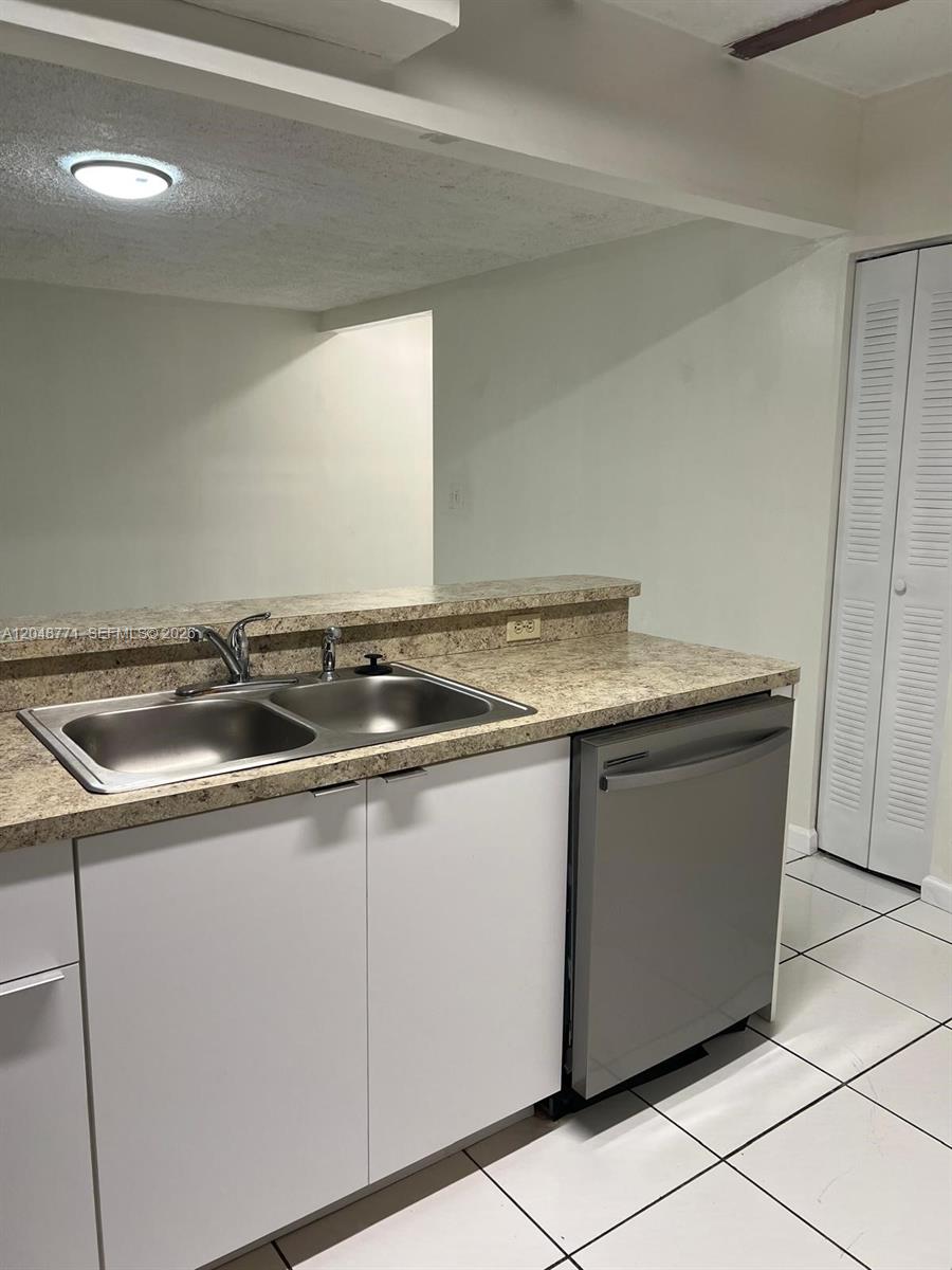 A kitchen features white cabinets, a double-basin sink, a dishwasher, and speckled laminate countertops — 10241 NW 9th St Cir # 5, Miami FL 33172, MIAMI, FL
