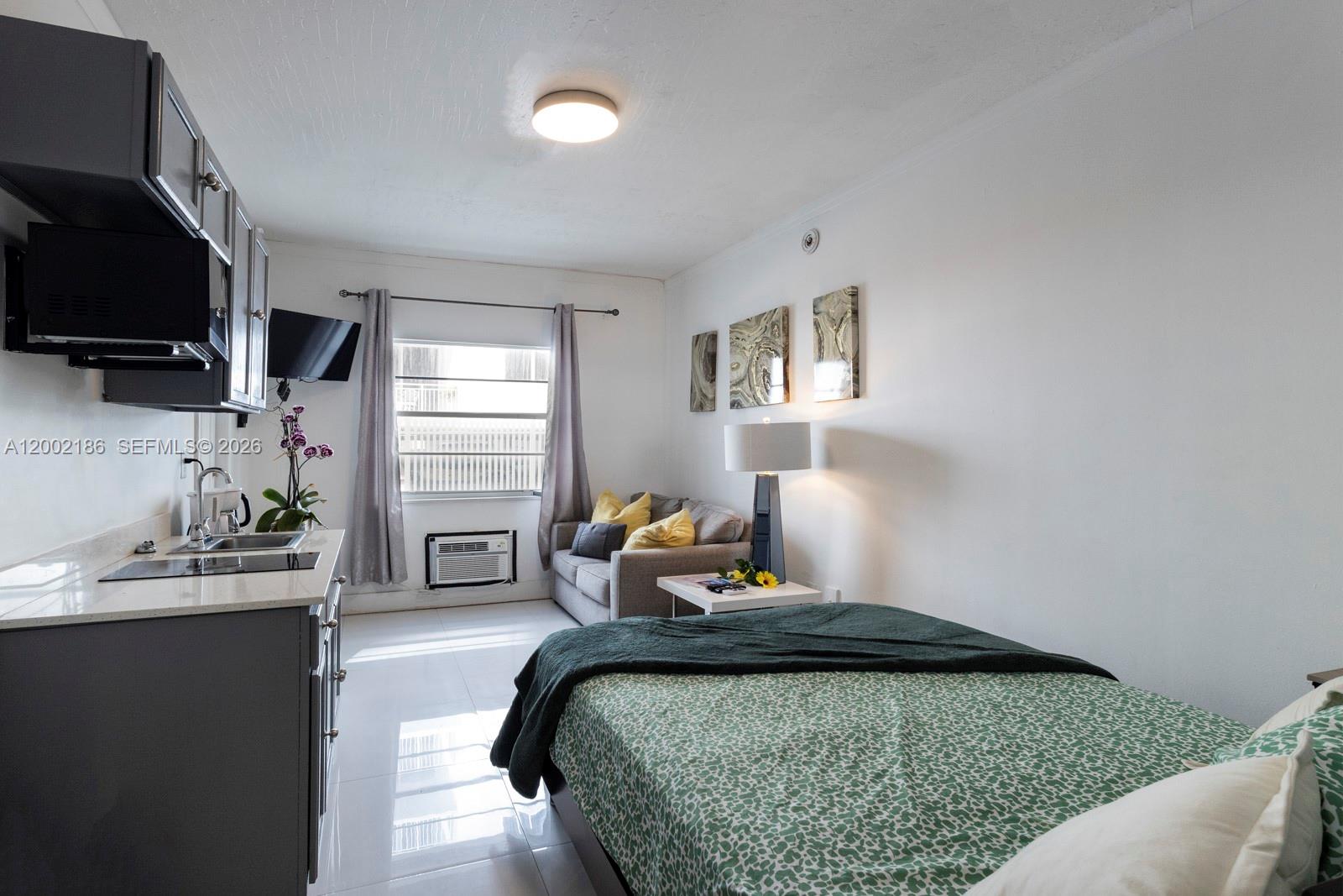 A studio apartment features a kitchenette, a bed, a small sofa, and a window — 335 Ocean Dr # 120, Miami Beach FL 33139, MIAMI BEACH, FL