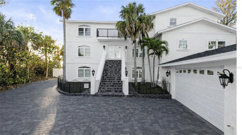 A three-story white house with a paved driveway, a central staircase, and an attached garage — 8030 MANASOTA KEY ROAD, ENGLEWOOD, FL