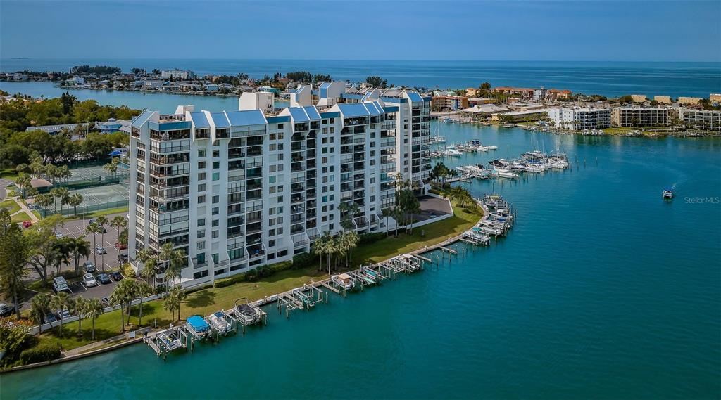 An aerial view of a multi-story waterfront condominium building with a private boat dock — 9495 BLIND PASS ROAD UNIT 205, ST PETE BEACH, FL