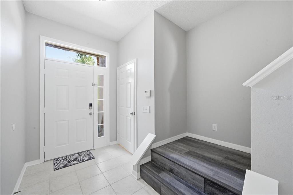 A modern kitchen features white upper cabinets, dark lower cabinets, stainless steel appliances, and an island — 752 VALLANCE WAY NE, ST PETERSBURG, FL