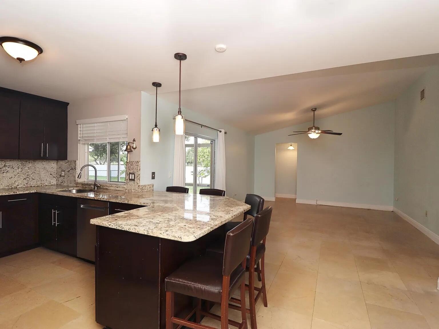 A kitchen with dark cabinets and granite countertops opens to a spacious living area — 6401 W Sedgewyck Cir W, Davie FL 33331, DAVIE, FL