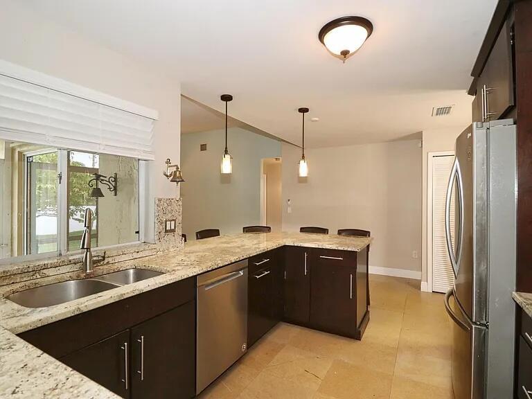 A kitchen features dark wood cabinets, granite countertops, stainless steel appliances, and pendant lighting — 6401 W Sedgewyck Cir W, Davie FL 33331, DAVIE, FL