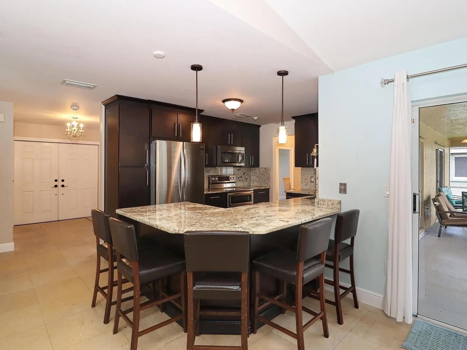 A kitchen with dark cabinets, granite countertops, a breakfast bar, and five bar stools — 6401 W Sedgewyck Cir W, Davie FL 33331, DAVIE, FL