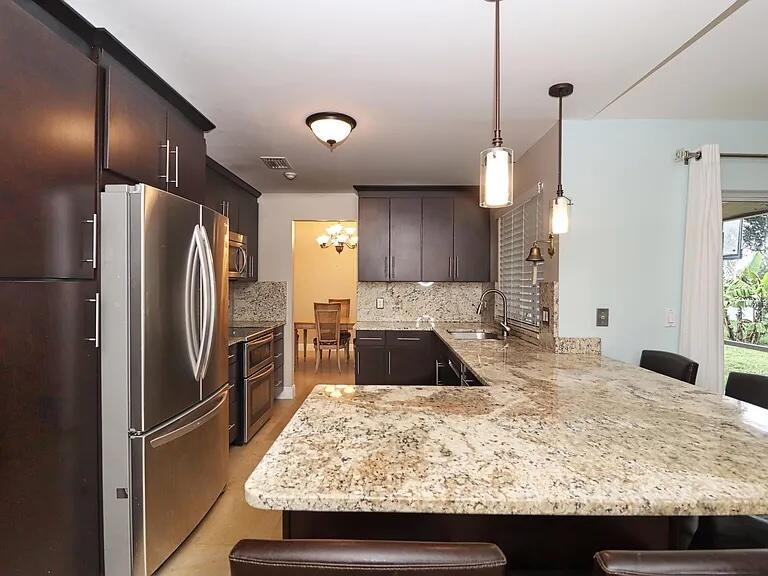 A kitchen features dark wood cabinets, granite countertops, stainless steel appliances, and pendant lighting — 6401 W Sedgewyck Cir W, Davie FL 33331, DAVIE, FL