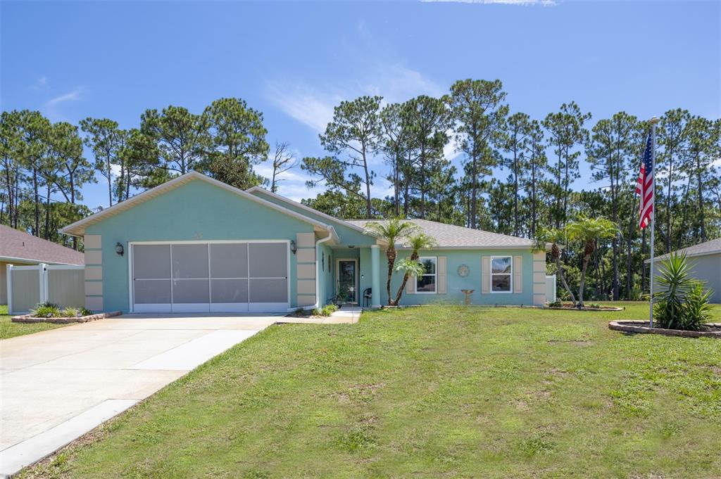 A light green single-story house with a two-car garage and a front yard — 69 PICKERING DRIVE, PALM COAST, FL