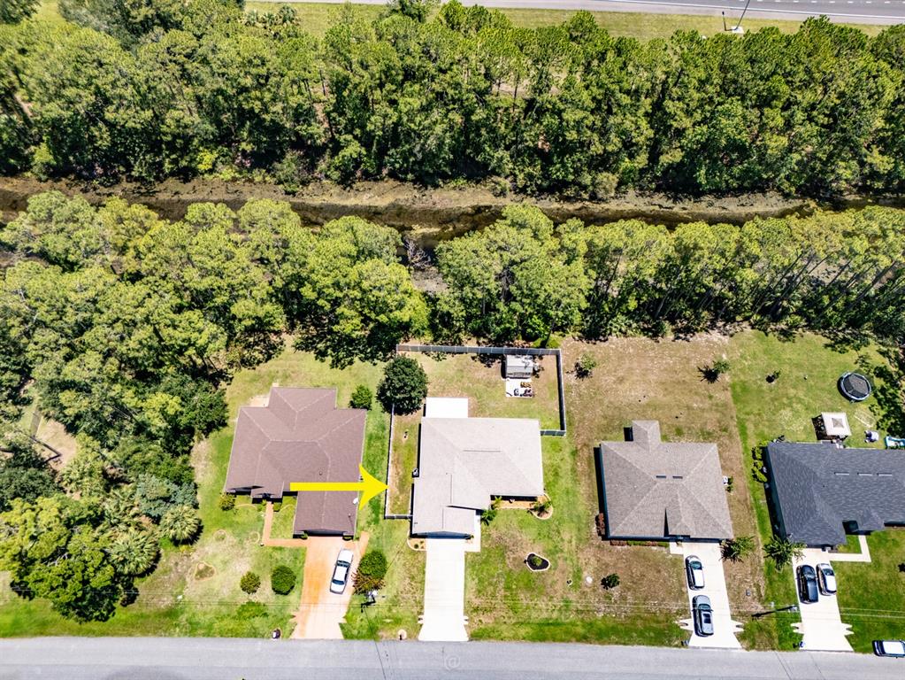Aerial view of a suburban street with houses, backyards, and a wooded area with a canal — 69 PICKERING DRIVE, PALM COAST, FL