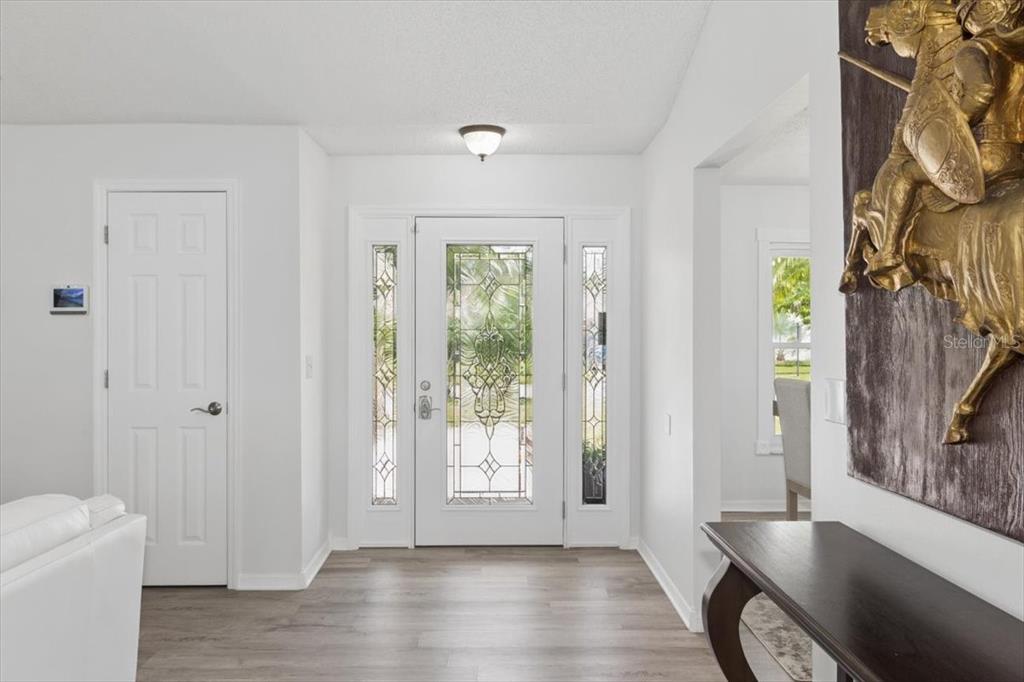 A bright entryway features a white front door with glass panels and light wood flooring — 4102 W BANK AVENUE, TAMPA, FL