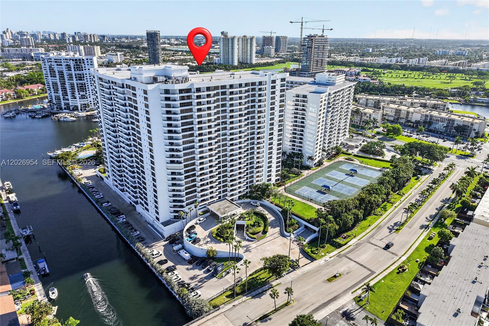 An aerial view shows a large white apartment building with a circular driveway and tennis courts — 2500 Parkview Dr # 1717, Hallandale Beach FL 33009, HALLANDALE BEACH, FL