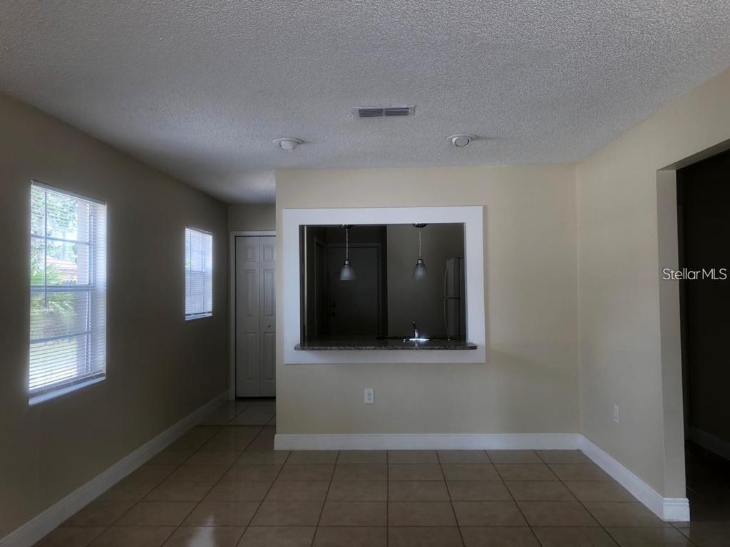 A dining area with tile floors features a pass-through window looking into the kitchen — 2839 8 IRON DRIVE UNIT 2839, LAKELAND, FL
