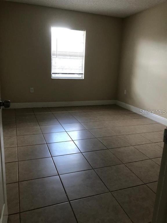 An empty room features beige tile flooring, light-colored walls, and a single window — 2839 8 IRON DRIVE UNIT 2839, LAKELAND, FL