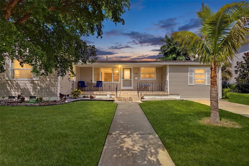 A single-story house with light-colored siding, a front porch, and a concrete walkway at dusk — 315 DURRANCE STREET, PUNTA GORDA, FL