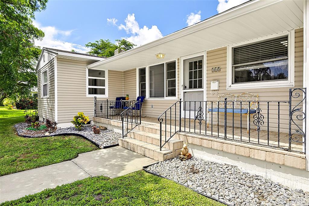 A beige house exterior features a front porch with black railings and a stone walkway — 315 DURRANCE STREET, PUNTA GORDA, FL