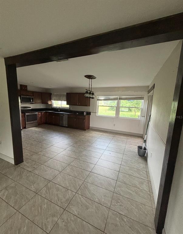 A kitchen and dining area with dark wood cabinets, tile flooring, and a wooden beam — 6735 APPOMATTOX DRIVE, NORTH PORT, FL