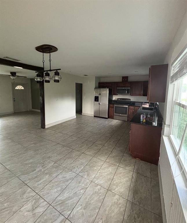 A kitchen with dark wood cabinets and stainless steel appliances opens to a tiled living area — 6735 APPOMATTOX DRIVE, NORTH PORT, FL
