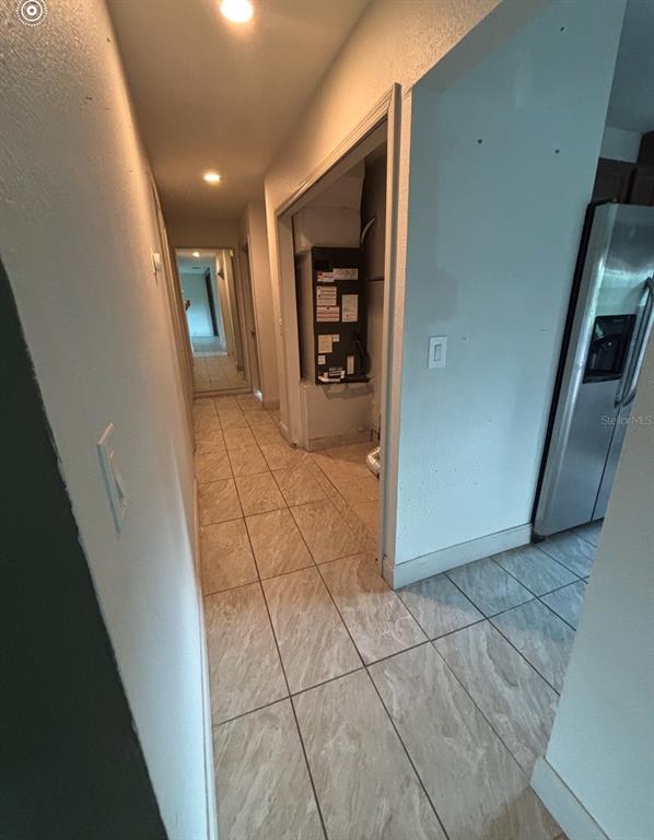 A hallway with tiled flooring leads to a utility closet containing an HVAC unit — 6735 APPOMATTOX DRIVE, NORTH PORT, FL