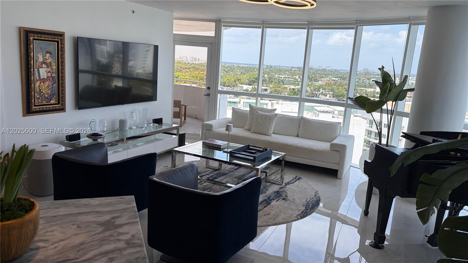 A modern living room features a white sofa, dark armchairs, a piano, and floor-to-ceiling windows — 6301 Collins Ave # 1207, Miami Beach FL 33141, MIAMI BEACH, FL