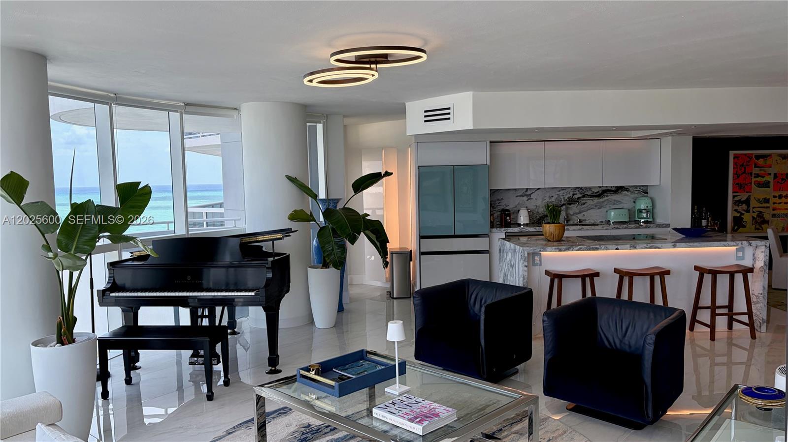 A modern living room features a grand piano, dark leather armchairs, and ocean views — 6301 Collins Ave # 1207, Miami Beach FL 33141, MIAMI BEACH, FL