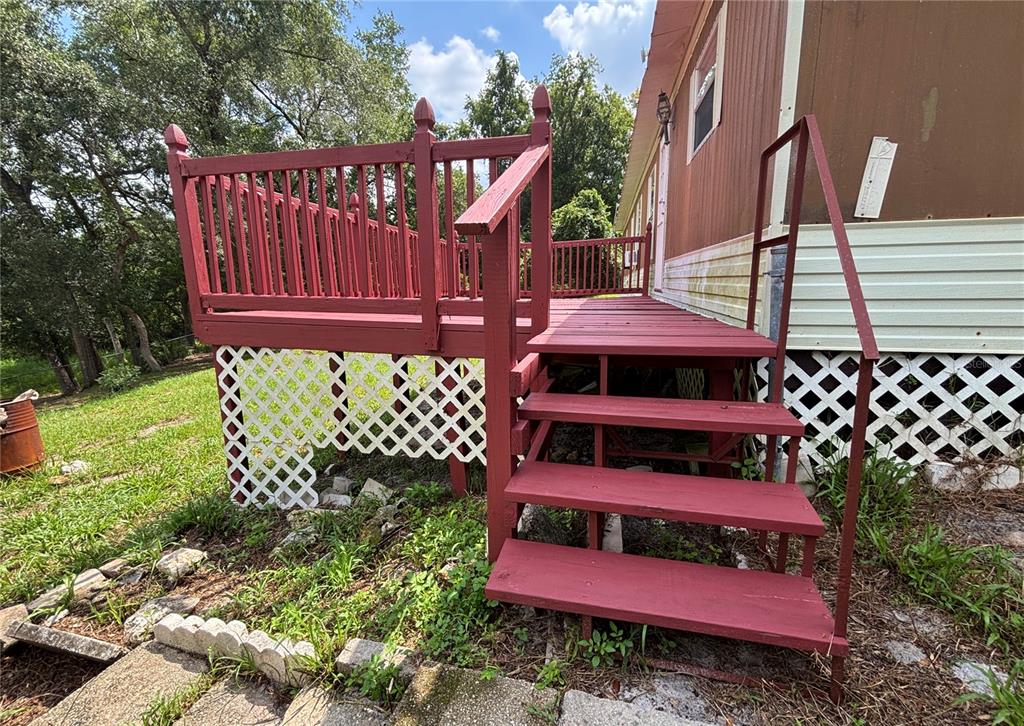 A red wooden deck with stairs and lattice skirting is attached to a mobile home — 18225 SE 22ND PLACE, SILVER SPRINGS, FL