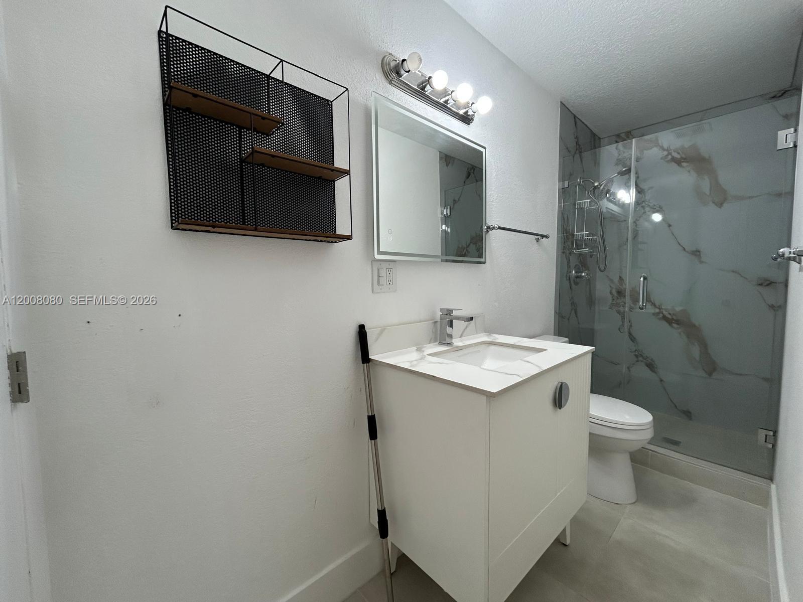 A modern bathroom features a white vanity, a glass-enclosed shower, and a black wall shelf — 14731 SW 170th Ter # 1, Miami FL 33187, MIAMI, FL